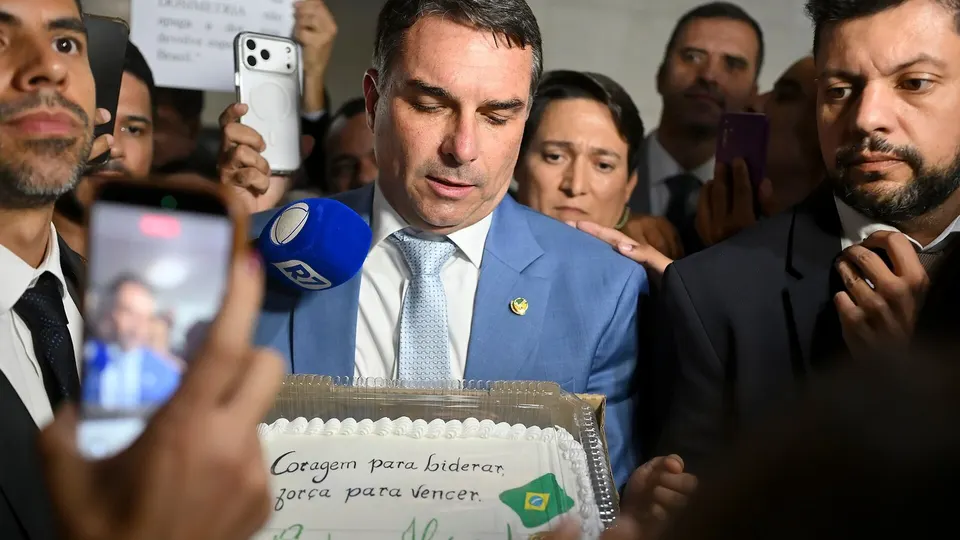 Flávio Bolsonaro, de terno, falando durante entrevista em corredor do Senado