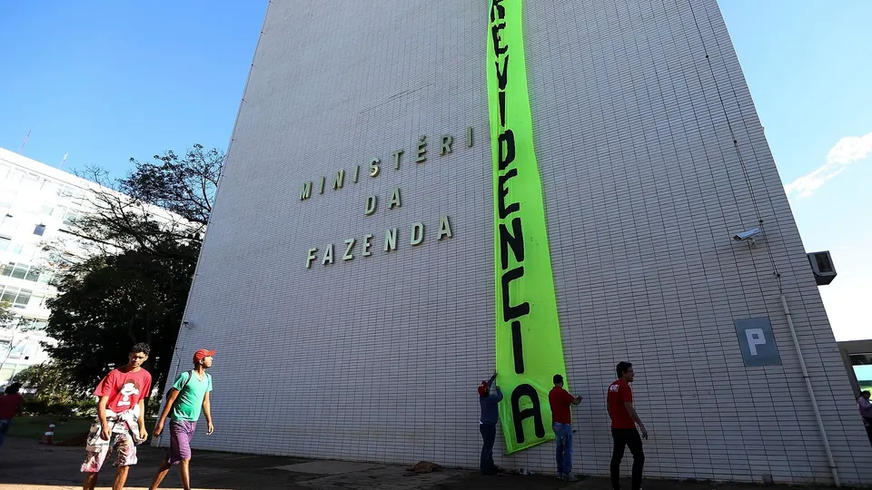 Pessoas reunidas na entrada do prédio do Ministério da Fazenda durante protesto