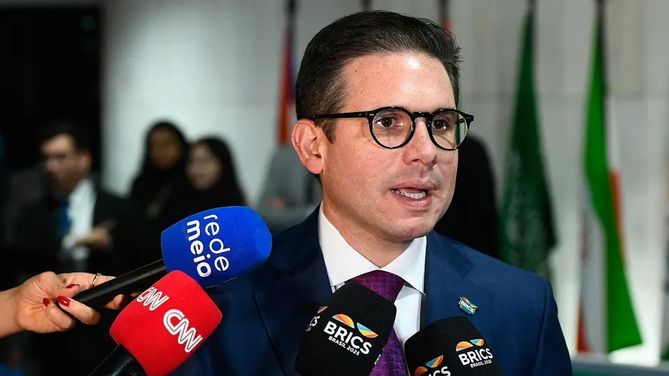 Hugo Motta, de terno, fala em entrevista coletiva com microfones à frente